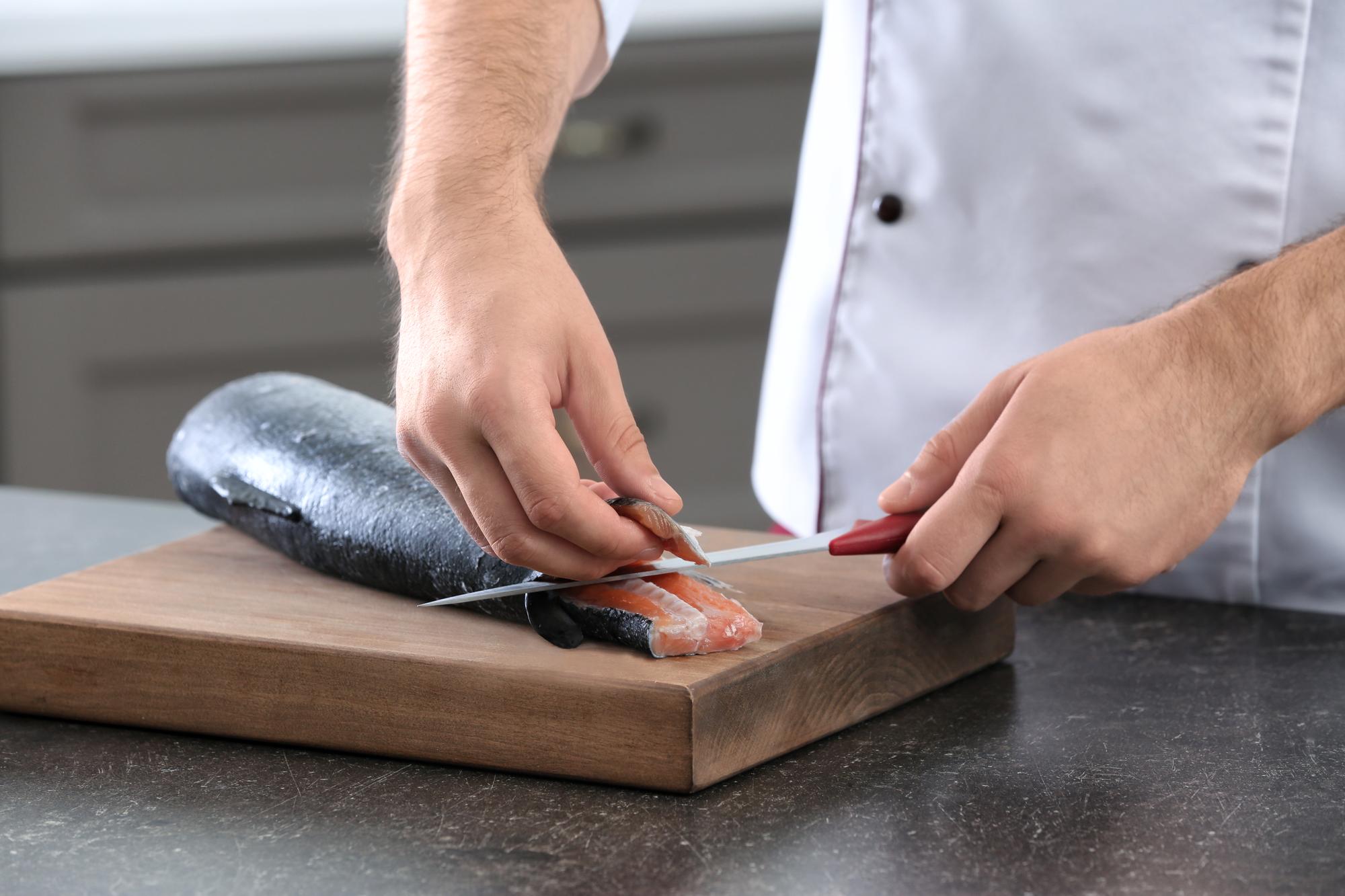 Chef slicing cured fish for plating