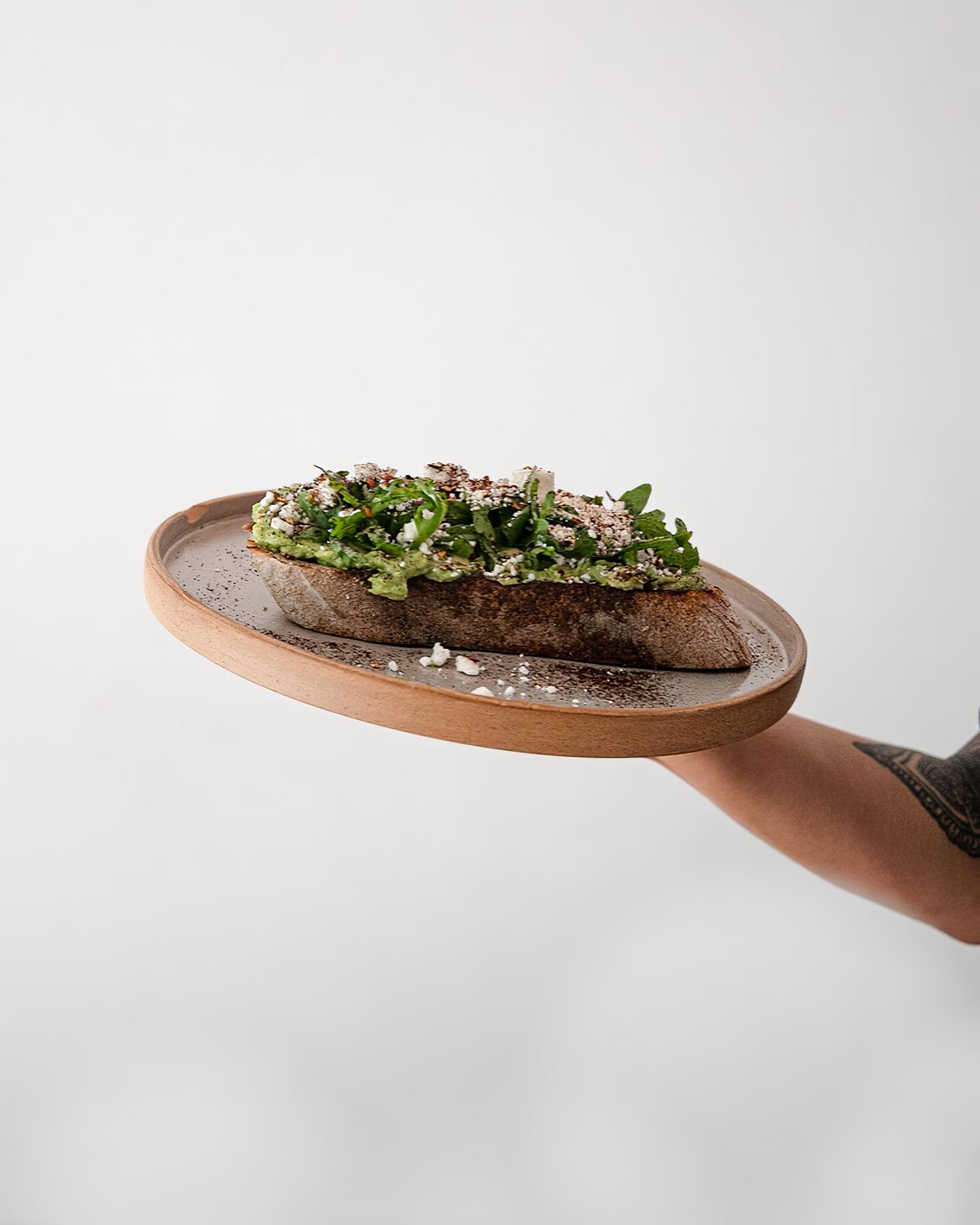 Chef plating modern tasting dish on wooden board
